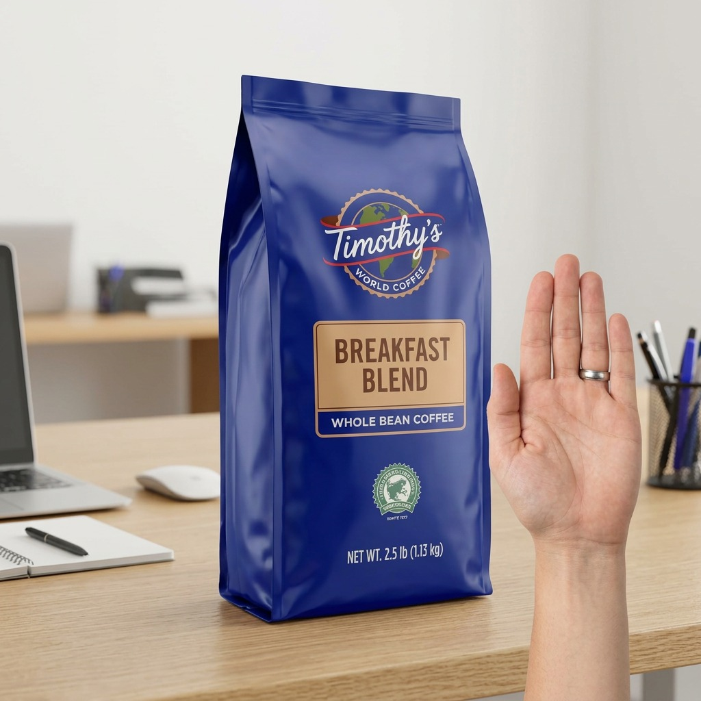 Timothy's Breakfast Blend Whole Bean Coffee bag on an office desk next to a hand for size scale.